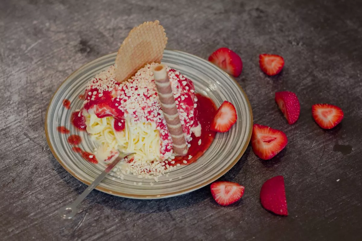 Spaghettieis mit Erdbeeren verziert auf einem bunten Teller